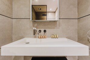 A modern bathroom with a large white sink, a mirror above it, and a door leading to another room. - PVH - Signature Livings - 2BR Penthouse (Dubai)