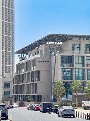 A modern building with a sign reading 'Signature Living.' It features a multi-story structure with a flat roof and large windows. - PVH - Signature Livings - 2BR Penthouse (Dubai)