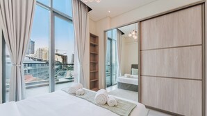 Une chambre d’hôtel moderne dotée d’un grand lit, offrant une vue sur la ville, et comprenant une armoire et une étagère intégrée.