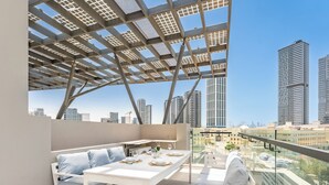Une terrasse sur le toit, avec une table dressée pour le dîner, un canapé et une vue sur les grands immeubles.