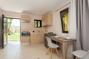A compact kitchen with a built-in oven, a small refrigerator, and a dining area with a table and chairs.