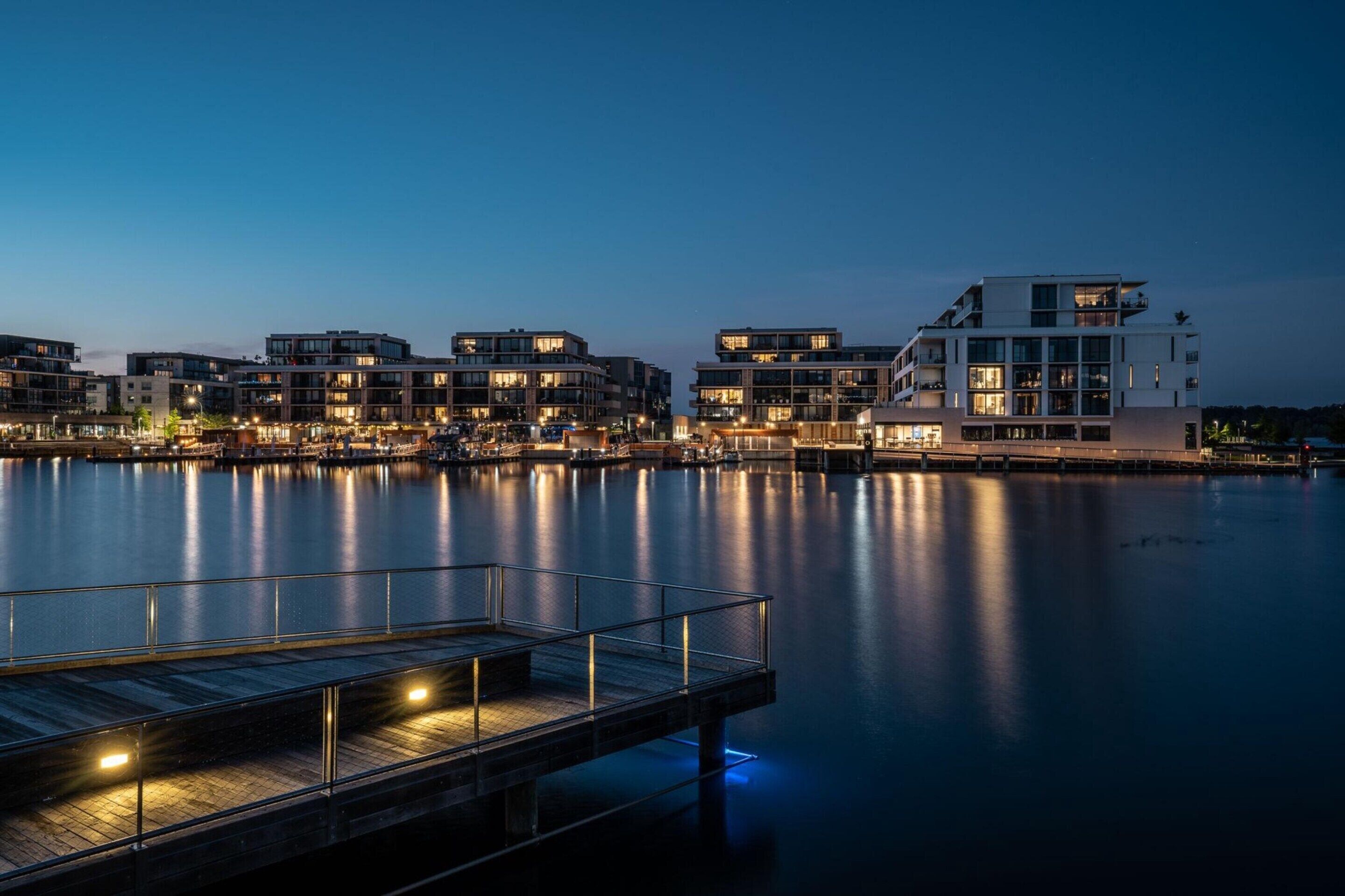 A waterfront property with modern buildings, a dock, and calm water.