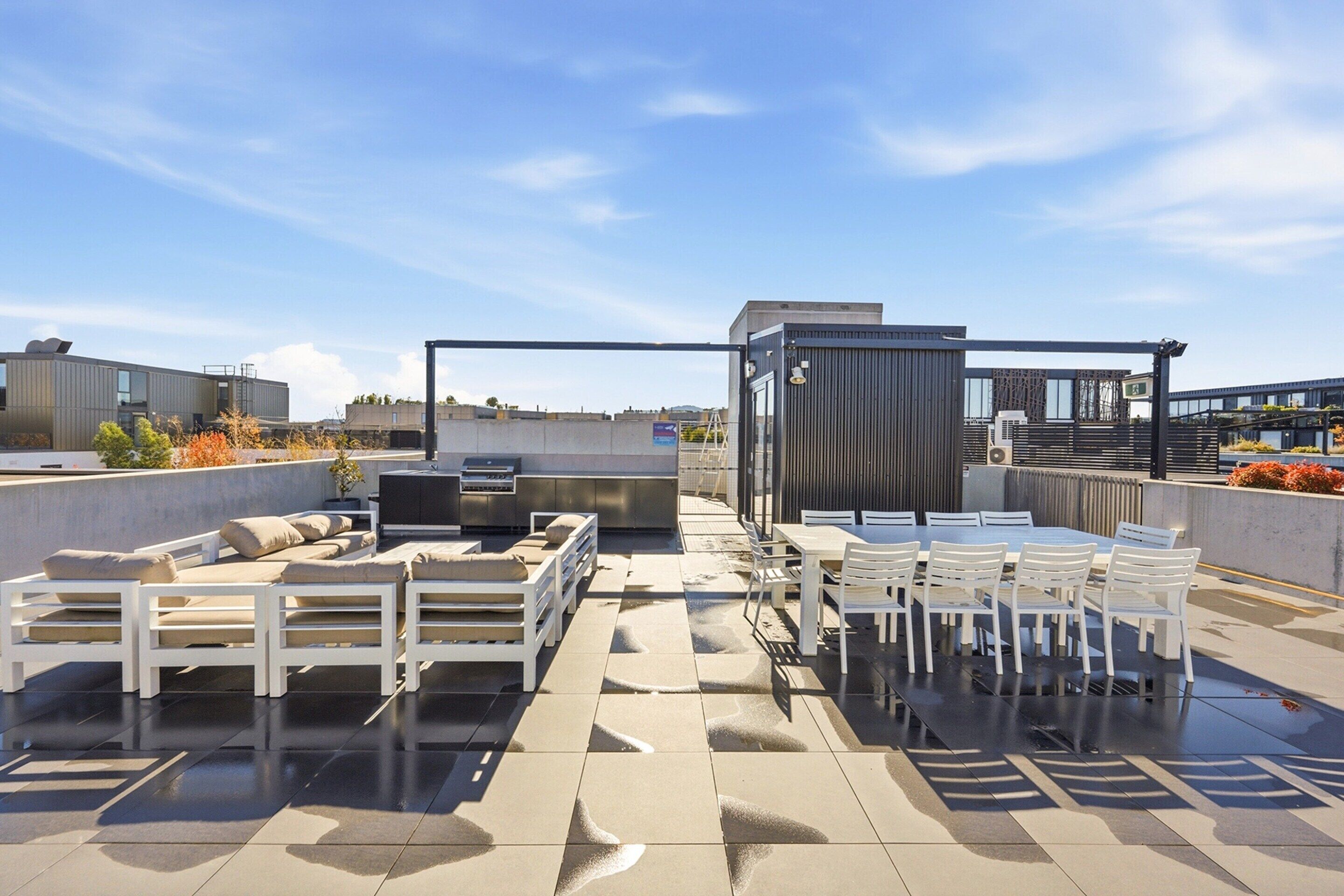 Eine Dachterrasse mit Sitzgelegenheiten im Freien, einem Grill und Blick auf die Stadt.