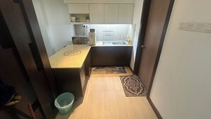 Una cocina compacta con armarios blancos, una encimera, un lavabo y una pequeña alfombra.