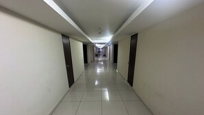 Un largo y estrecho pasillo de hotel con suelo de baldosas y puertas a ambos lados.