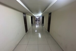 A long, narrow hotel corridor with a tiled floor and doors on both sides. - Ain Studio Apartment (Kota Bharu)