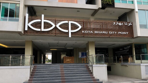 Un edificio con un letrero que dice 'KOTA BHARU CITY POINT' y una escalera que conduce a la entrada.