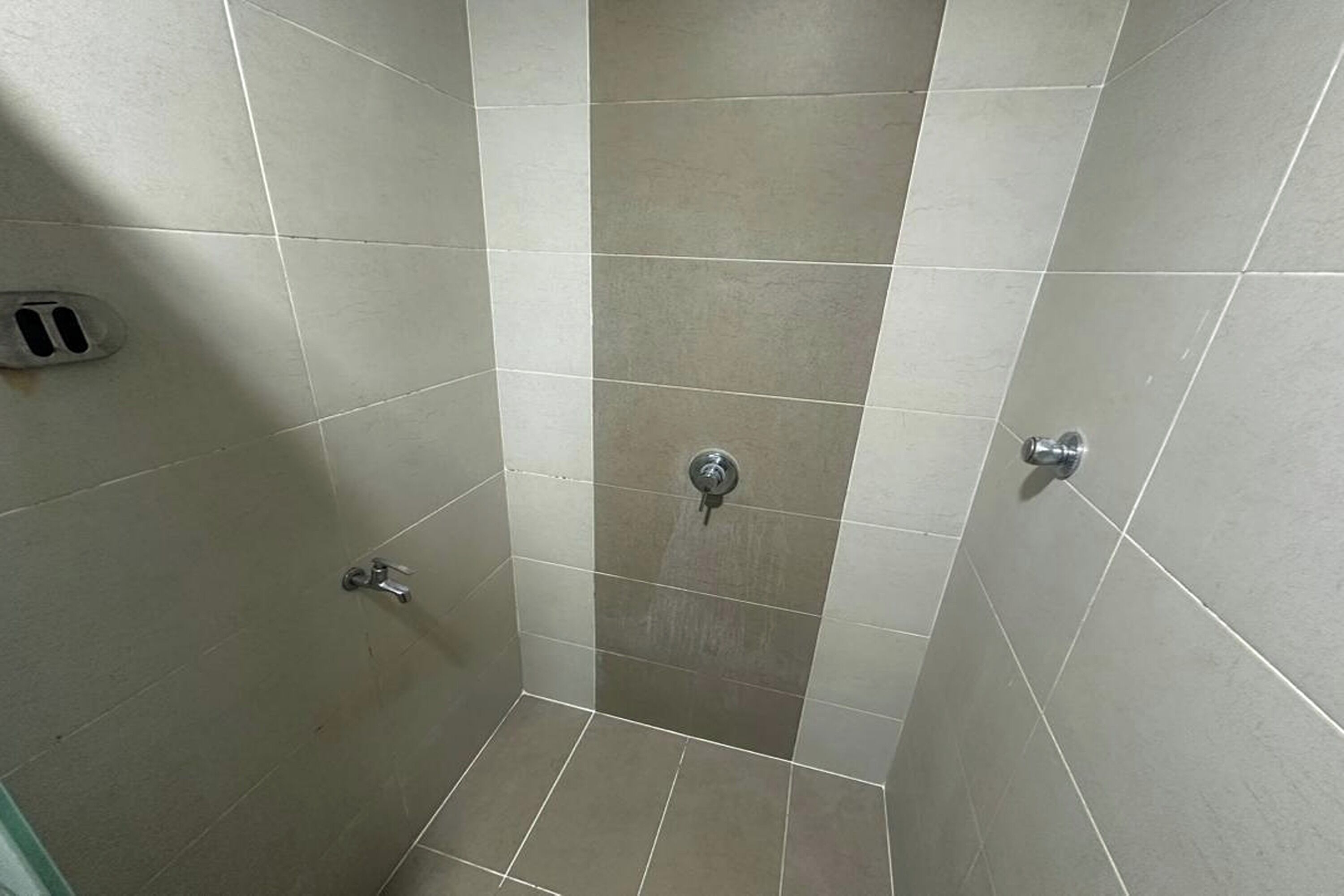 A small, tiled shower area with a drain and a faucet.