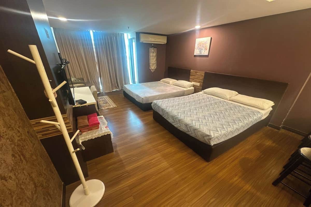 A hotel room with a large bed, a smaller bed, a desk, and a chair.