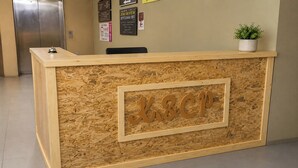 Una recepción con detalles de madera, una planta en maceta encima y un cartel con 'K&CT' en el centro.