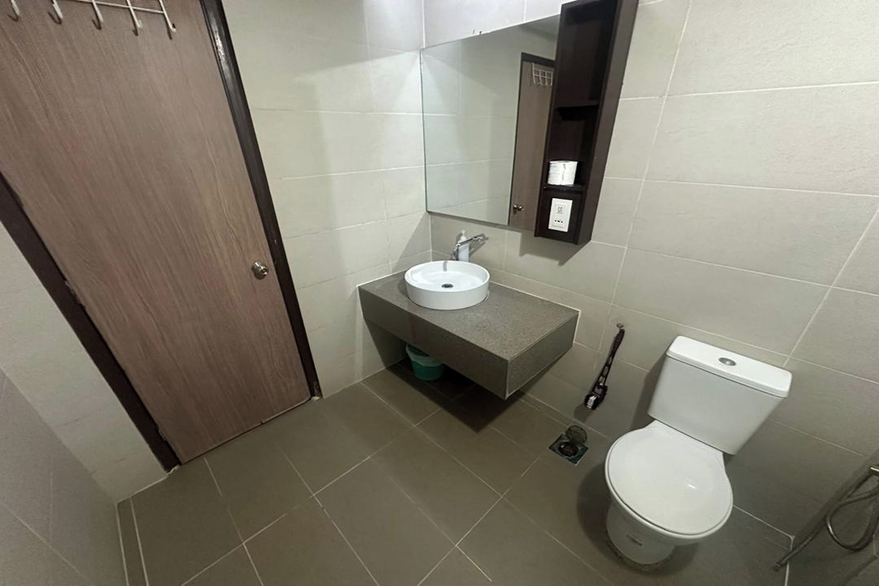 A bathroom with a wooden door, a white sink, a toilet, and a mirror.