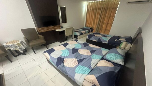 Habitación de hotel con una cama grande, un escritorio, una silla, una mesita y un televisor.
