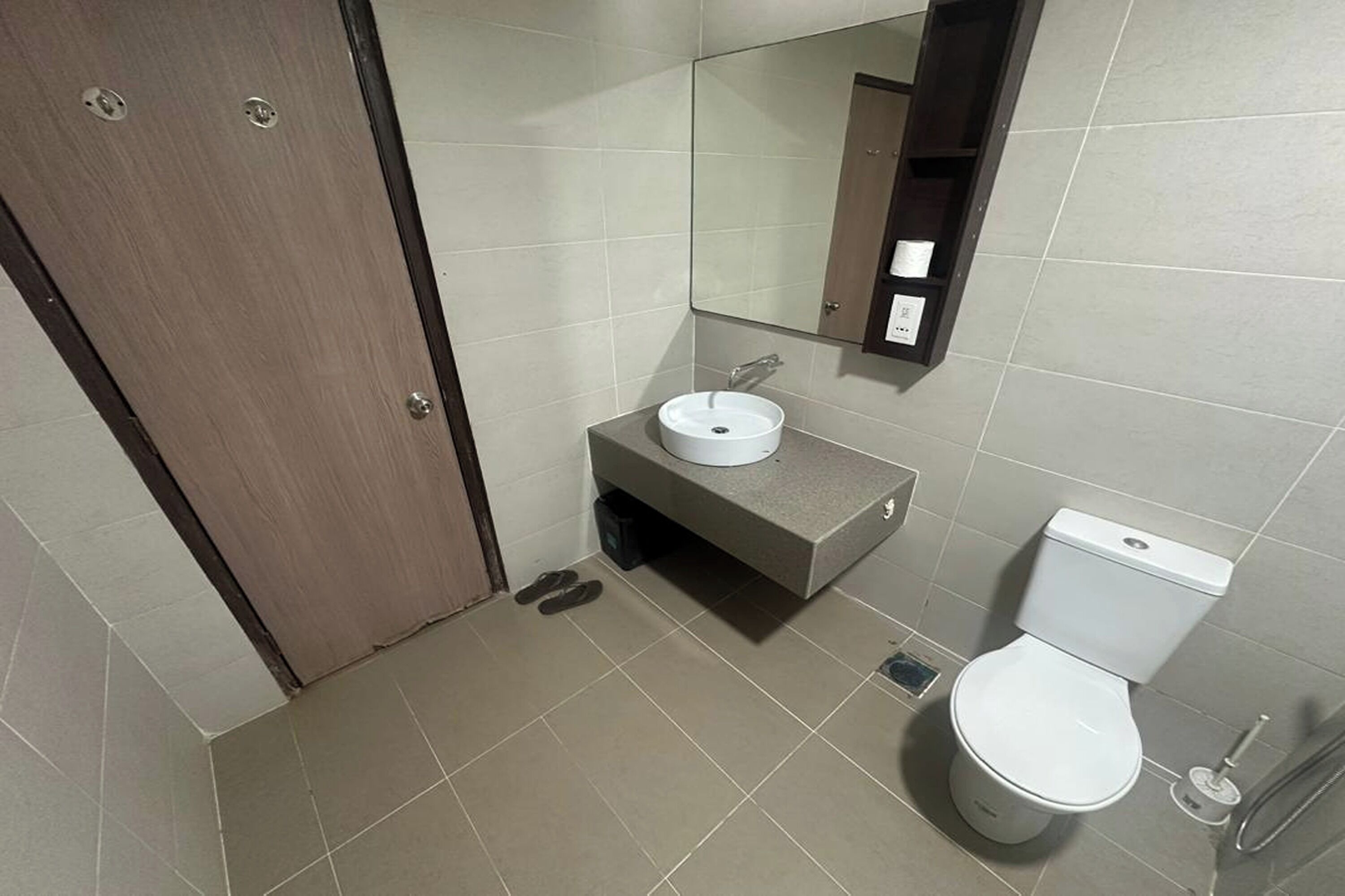 Un baño con inodoro, lavamanos, espejo y puerta.