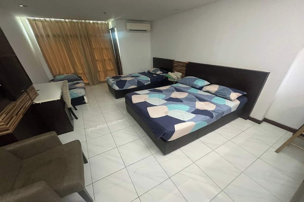 A hotel room with two beds, a desk, and a chair.