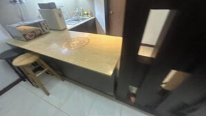 Una cocina compacta con mostrador, taburetes y refrigerador.