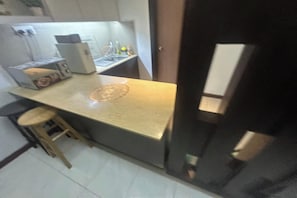 Una cocina compacta con mostrador, taburetes y refrigerador.