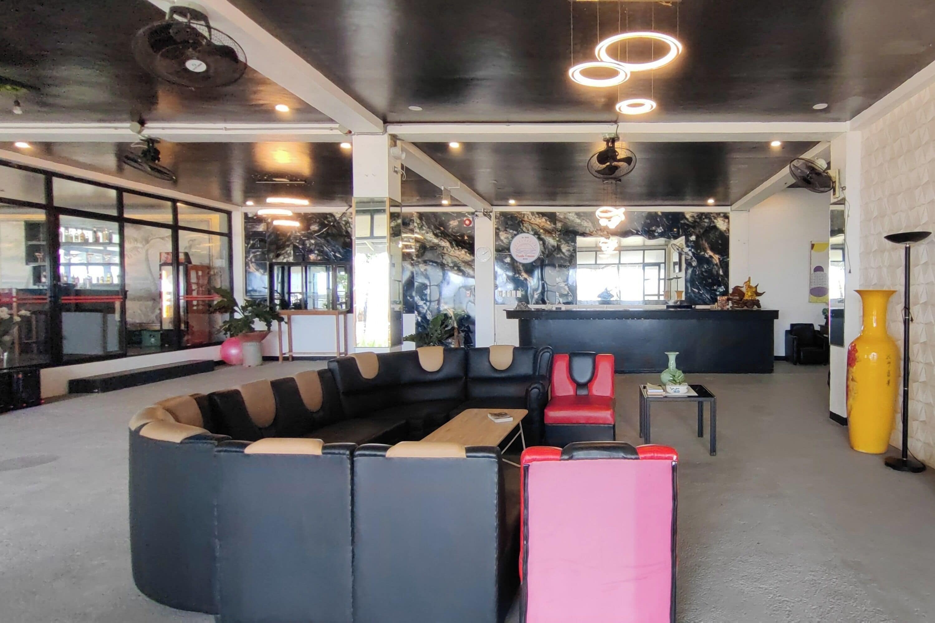 Un interior moderno con una zona de estar curva, un mostrador de recepción y un espejo grande.