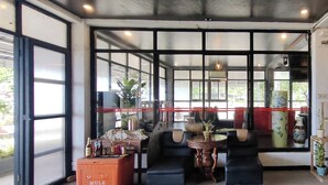 A room with large windows, a sofa, a small table, and a crate labeled 'MULE'. - Puerto Paraiso Hostel (Puerto Princesa)