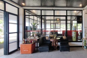 Una habitación con ventanas amplias, un sofá, una mesita y un caja etiquetada 'MULE'.