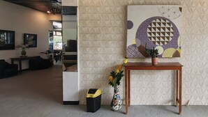 A room with a geometric-patterned wall, a wooden table with a vase, and a trash bin. - Puerto Paraiso Hostel (Puerto Princesa)
