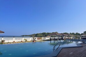 A pool with a wooden deck, lounge chairs, and umbrellas.