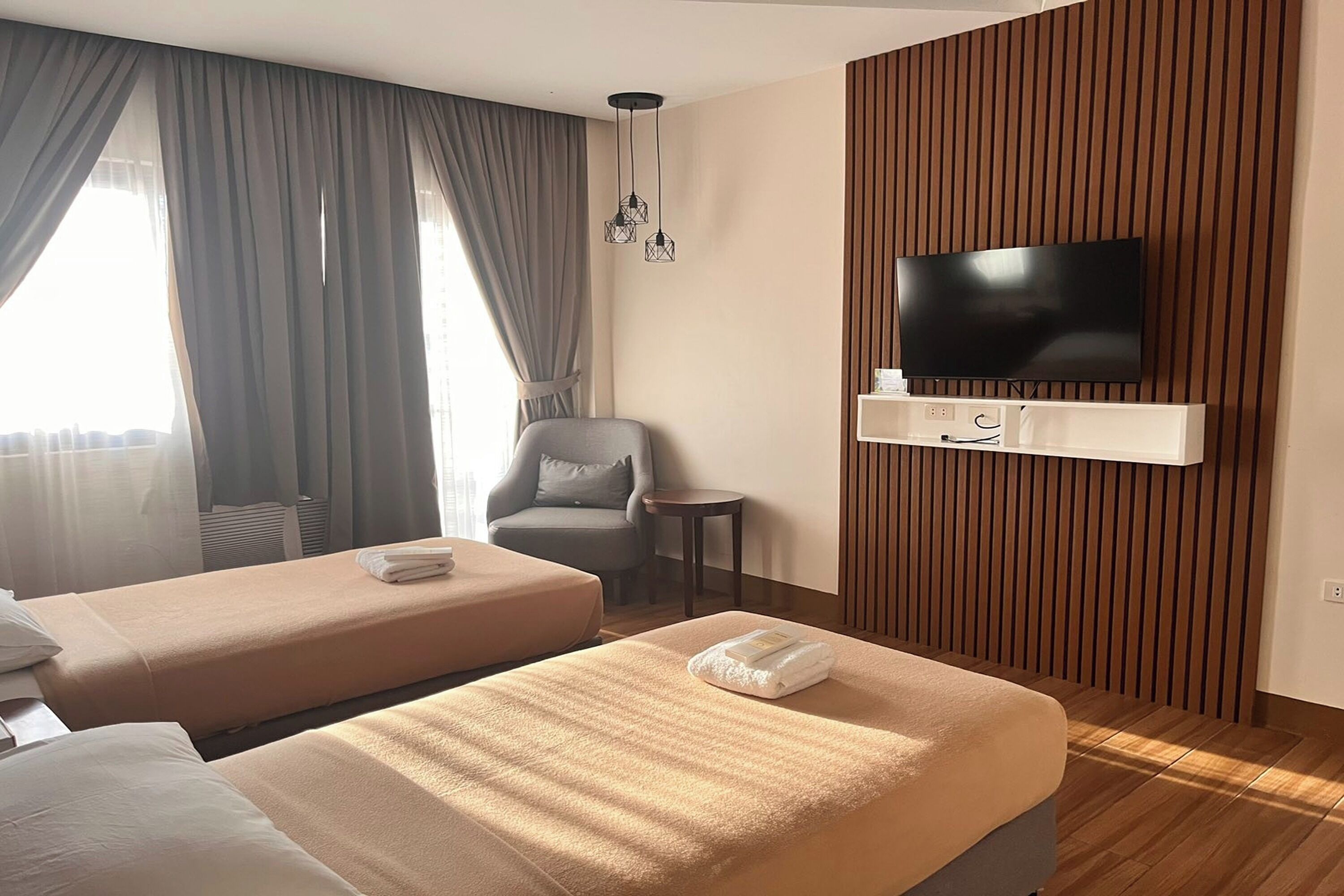 Habitación de hotel con dos camas, televisión, una silla y una mesita.