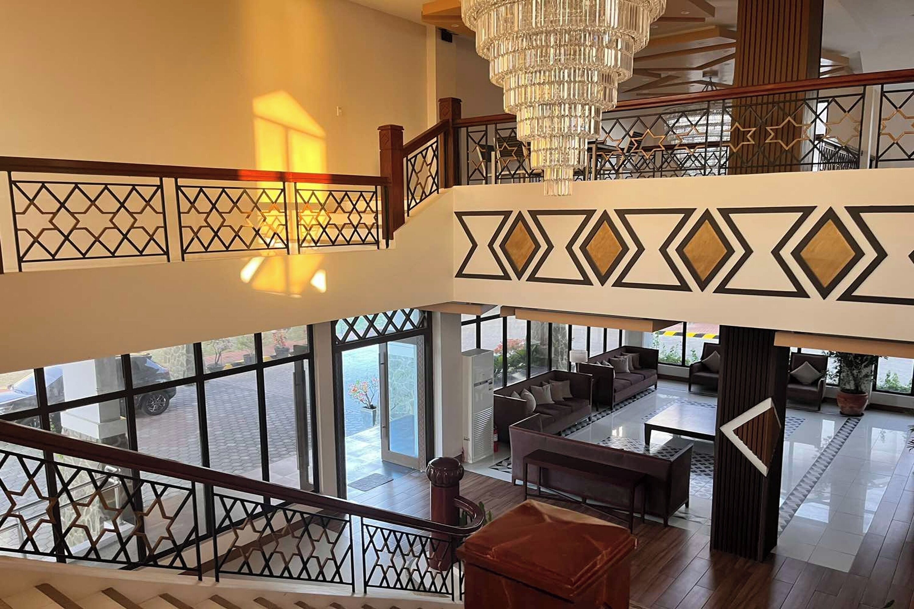 Vestíbulo de hotel con escalera, zona de estar y amplias ventanas.