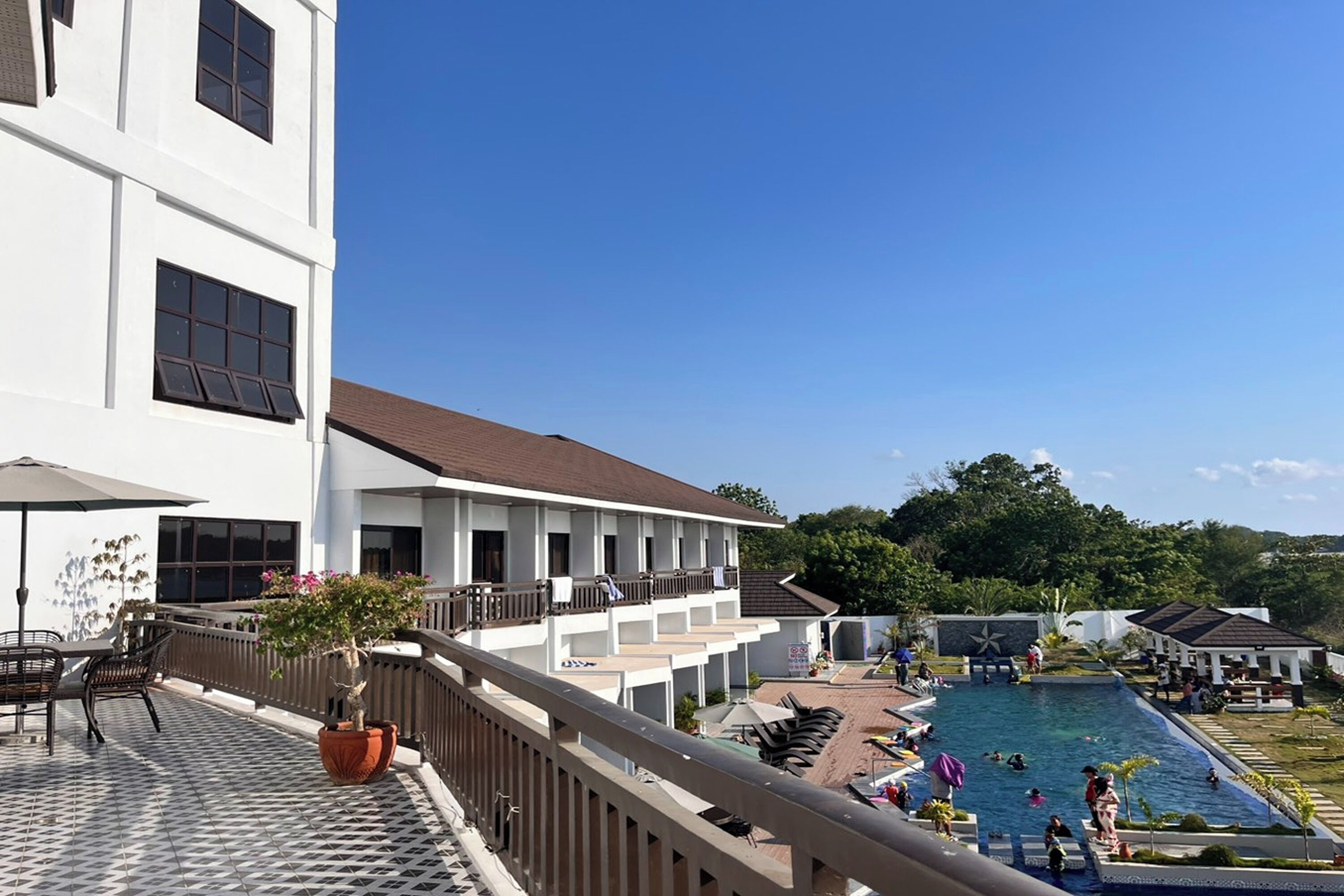 A hotel with a pool area, outdoor seating, and a view of the pool.