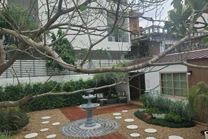 A garden with a central fountain, surrounded by stepping stones and various plants. - Sathorn Hideaway (Bangkok)