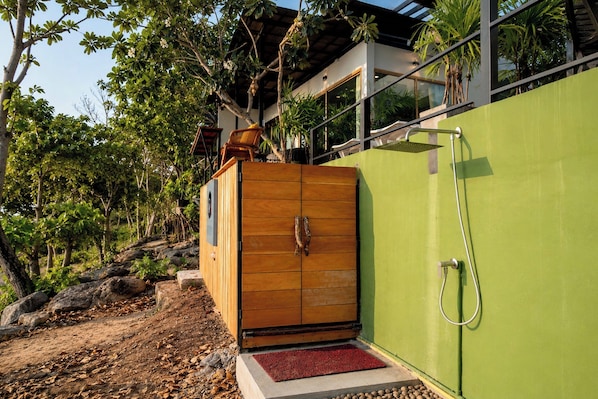 A wooden cabinet with a red mat, a green wall, and a shower area.