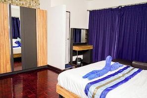 Ein Hotelzimmer mit Bett, Schrank, Spiegel und Schreibtisch.