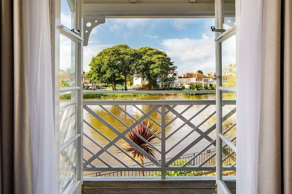 A view from a balcony with a railing, a tree, and a body of water.