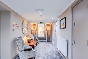 A hallway with a dining area featuring a table and chairs, a radiator, and a framed picture on the wall. - Sunday London Staines-upon-Thames Heathrow T9 - Twin Room with River View (London)