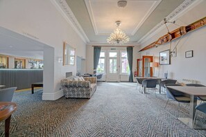En hotellobby med ett mönstrat golv, en kristallkrona, en receptionsdisk och en sittgrupp med stolar och en soffa.
