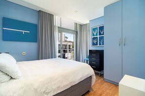 A bedroom with a bed, a wardrobe, a desk, and a window with curtains. - Luxurious 2-Bedroom Penthouse with Stunning Views in Central Cape Town (Cape Town)