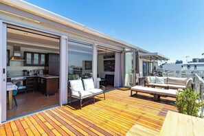 A modern deck with a kitchen area, sliding glass doors, and outdoor seating. - Luxurious 2-Bedroom Penthouse with Stunning Views in Central Cape Town (Cape Town)