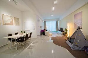 A modern living room with a dining area, a sofa, a tent, and artwork on the walls.
