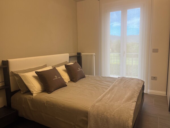 Un dormitorio con una cama, dos almohadas, un radiador y una ventana con vistas.