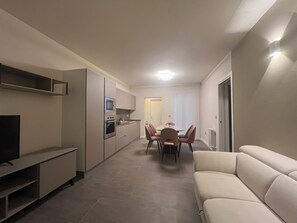 A modern kitchen with built-in appliances, a dining area with a table and chairs, and a living area with a sofa. - Elegance and Comfort in the Green Heart of Umbria "Suite Calipso" (Vernazzano Basso)