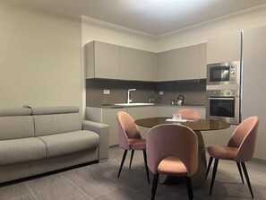 Una cocina moderna con comedor, sofá gris y sillas rosadas.