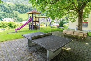 A playground with a slide and swings, a bench, and a paved area. - 4Seasons | Morschach | Family Apartment | Mountain View (Morschach)