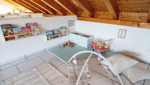 Une salle de jeux pour enfants avec un lit en mezzanine, des étagères de rangement et des jouets.