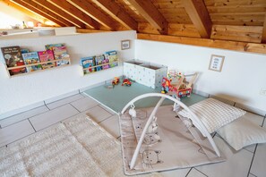 Ein Spielzimmer mit Hochbett, Regalen und Spielzeug.