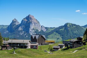 A mountain village with traditional wooden houses, a prominent mountain peak in the background, and a clear sky. - 4Seasons | Morschach | Family Apartment | Mountain View (Morschach)