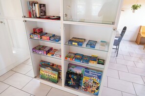 A glass-fronted shelf unit with various board games and books. - 4Seasons | Morschach | Family Apartment | Mountain View (Morschach)