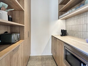 Una cocina moderna con armarios de madera, horno empotrado y cafetera sobre la encimera.
