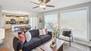 Ein modernes Wohnzimmer mit einer Couch, einem Couchtisch und einem Deckenventilator.