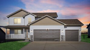Ein zweistöckiges Haus mit Garage, überdachter Veranda und gepflegtem Rasen.