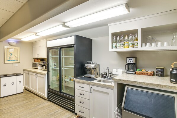 A kitchen with a refrigerator, coffee maker, and cabinets.