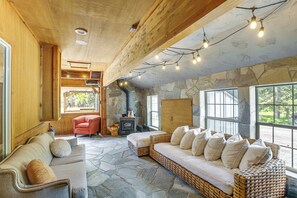 A cozy interior with a stone wall, wooden ceiling, and a wicker sofa with cushions.